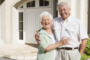 A senior couple outside smiling in front of their home